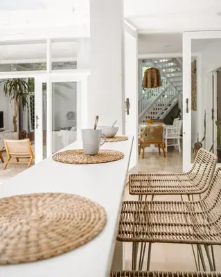 a white kitchen with rattan chairs and a table at THE HIDDEN TREE CANGGU 100 meter to beach in Canggu