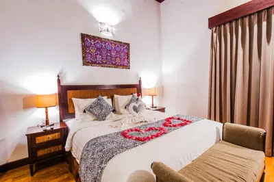 a bedroom with a large bed and a chair at Aldeoz Grand Kancana Villas Resort Bali in Kerobokan