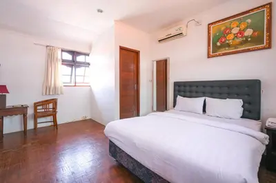 a bedroom with a large bed and a desk at Ceria Guesthouse Seminyak Mitra RedDoorz in Seminyak