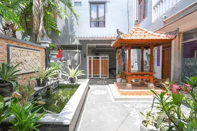 a garden with a koi pond in front of a house at Ceria Guesthouse Seminyak Mitra RedDoorz in Seminyak