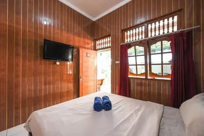 a bedroom with a bed with two blue shoes on it at Ceria Guesthouse Seminyak Mitra RedDoorz in Seminyak