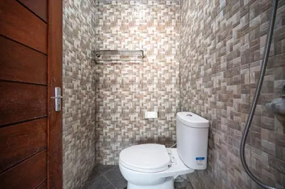 a bathroom with a toilet and a shower at Ceria Guesthouse Seminyak Mitra RedDoorz in Seminyak