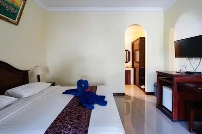 a blue ribbon sitting on a bed in a bedroom at Taman Ayu Legian Hotel in Legian