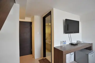 a room with a television on a wall with a desk at Ganga Hotel & Apartment in Denpasar