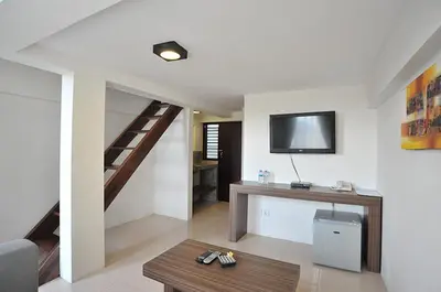 a living room with a staircase and a television on the wall at Ganga Hotel & Apartment in Denpasar