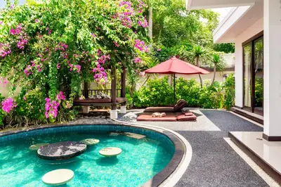 a swimming pool in a garden with pink flowers at D&G Villas Nusa Dua in Nusa Dua