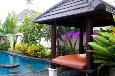 a bench sitting next to a swimming pool at D&G Villas Nusa Dua in Nusa Dua