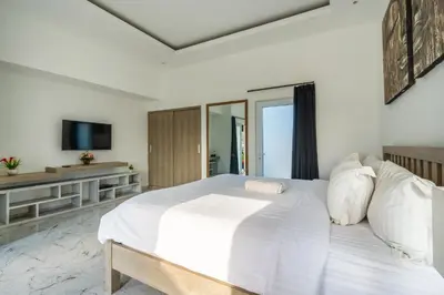 a bedroom with a white bed and a television at La Terra Villas Canggu Kuta Bali in Canggu