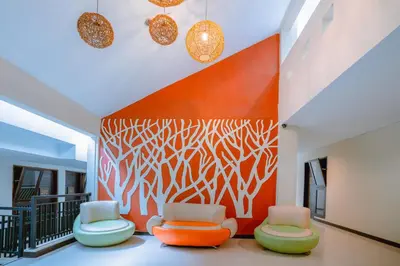 a room with three chairs and a wall with a painting at Balitone Guest House in Denpasar
