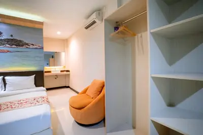 a bedroom with a bed and a chair in a room at Balitone Guest House in Denpasar