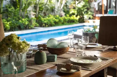 a wooden table with glasses and a bowl of food at Villa Alu Lima in Seminyak
