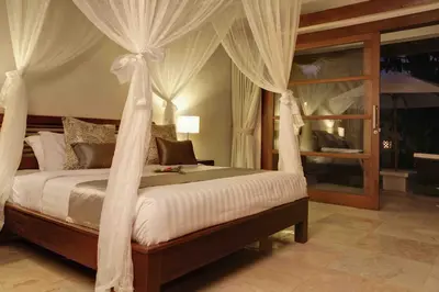 a bedroom with a canopy bed with white drapes at Villa Alu Lima in Seminyak