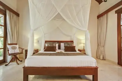 a bedroom with a canopy bed with curtains at Villa Alu Lima in Seminyak