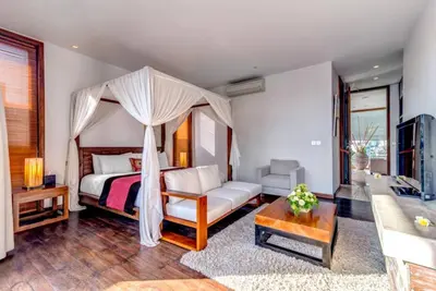 a bedroom with a canopy bed and a living room at Villa De Jiwa 495 Seminyak in Seminyak