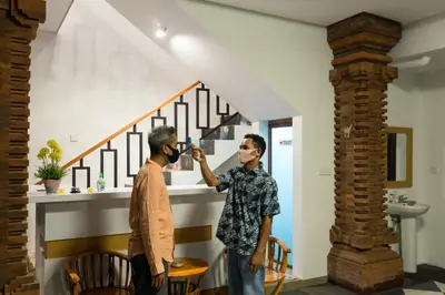 two men standing in a living room looking at a mirror at Pondok Bobo Seminyak in Seminyak
