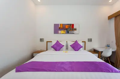 a bedroom with a large bed with purple pillows at Pondok Bobo Seminyak in Seminyak