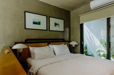 a bedroom with a bed with two lamps and a window at T Lofts in Seminyak