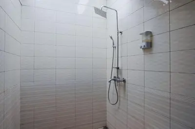 a shower with a hose in a white tiled bathroom at Balitung Villa Seminyak in Seminyak