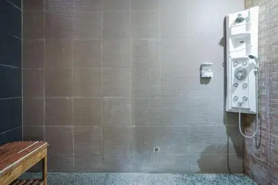 a bathroom with a shower with a phone on the wall at Balitung Villa Seminyak in Seminyak