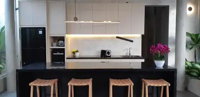a kitchen with a black counter and stools at Villa Teejay - architect-designed luxury in perfect Petitenget location in Seminyak