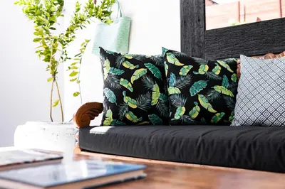a black couch with pillows and a table with a laptop at Villa Revo in Seminyak
