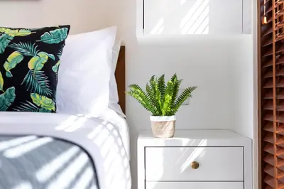 a bedroom with a bed and a plant on a nightstand at Villa Revo in Seminyak