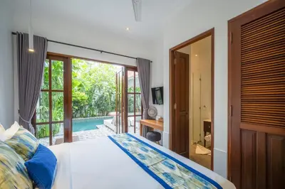 a bedroom with a bed and a door to a pool at Villa Jolaine in Seminyak