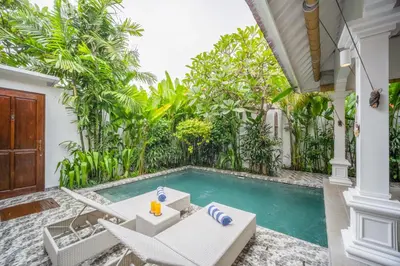 an outdoor patio with a swimming pool and a villa at Villa Jolaine in Seminyak