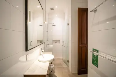 a white bathroom with a sink and a shower at Villa Jolaine in Seminyak