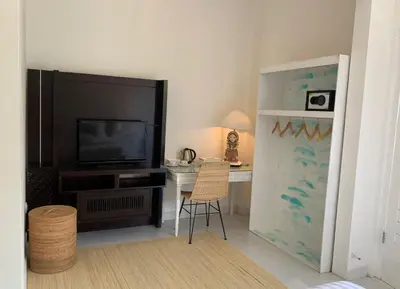 a living room with a television and a desk with a chair at NIKINIKO Beach House by Lolavillas - 100mts to the beach in Canggu