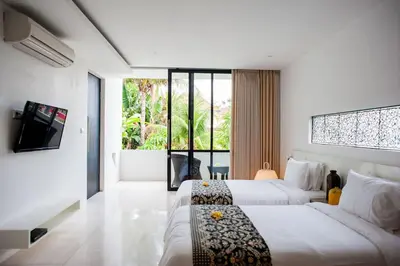 a hotel room with two beds and a large window at Villa Muse Seminyak - 500 meters from beach in Seminyak