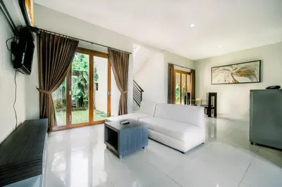 a living room with a white couch and a tv at ABISHA Resort Jimbaran in Jimbaran