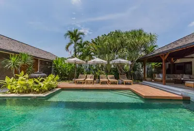 a pool with chairs and umbrellas next to a house at Tropical 5BR Villa & 20m Pool, Sleeps 12 in Seminyak
