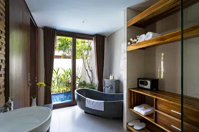 a bathroom with a tub and a large window at The Calna Villa Bali in Kuta