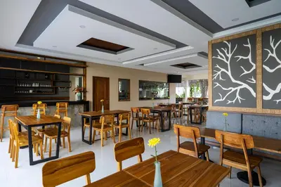 a restaurant with wooden tables and chairs and a large wall at The Calna Villa Bali in Kuta
