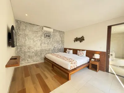 a bedroom with a bed and a bath room at The Calna Villa Bali in Kuta