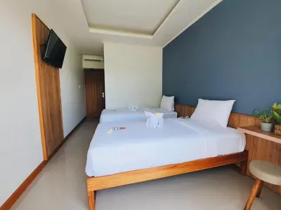 a bedroom with two beds and a tv in it at RakaAyu Kuta in Kuta