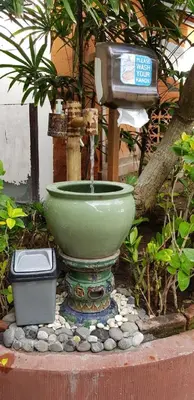 a water fountain with a green bowl in a garden at Puri Naga Beachfront Cottages in Legian