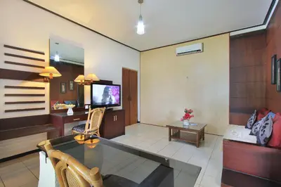 a living room with a couch and a tv in it at Puri Naga Beachfront Cottages in Legian