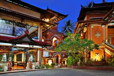 a group of buildings with a tree in the courtyard at Puri Naga Beachfront Cottages in Legian