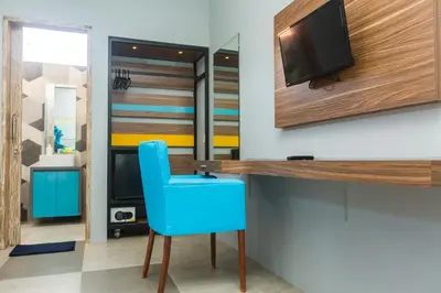 a room with a blue chair and a tv on a wall at 7Rooms Villa Seminyak in Seminyak