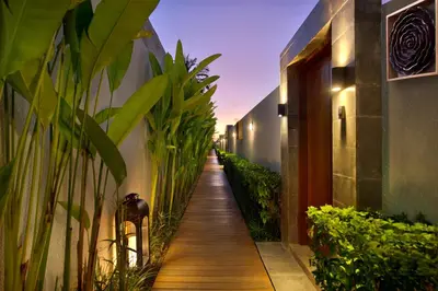 a wooden walkway between two buildings with plants at The Claremont Luxury Villas in Seminyak