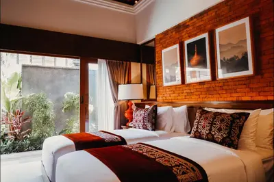 two beds in a room with a large window at Sampatti Villas in Seminyak