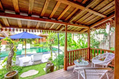 an outdoor deck with a table and chairs and an umbrella at Moson Villa Legian in Legian