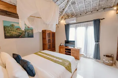 a bedroom with a large white bed and a television at Moson Villa Legian in Legian