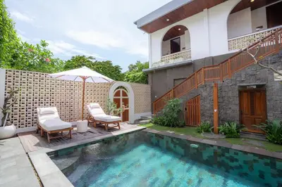 a house with a swimming pool and two chairs and an umbrella at Moson Villa Legian in Legian