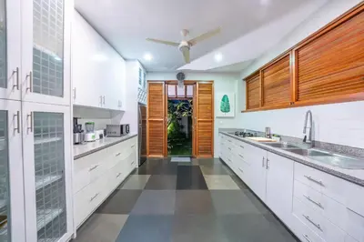 a kitchen with white cabinets and a ceiling fan at Villa Litera Canggu Bali in Canggu
