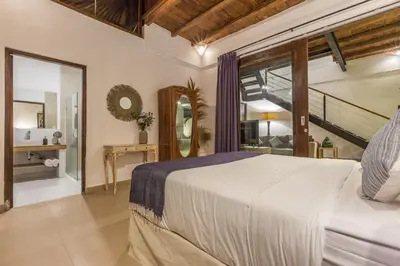 a bedroom with a large bed and a staircase at Villa Bunga 1 in Seminyak