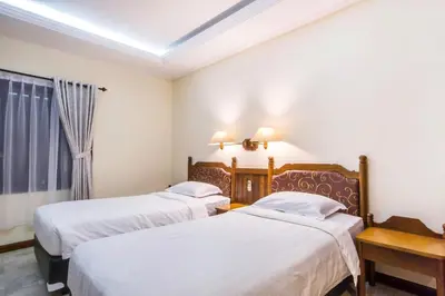a hotel room with two beds and a window at Bali Bungalo Hotel in Kuta