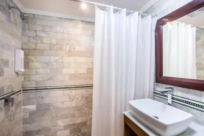 a bathroom with a sink and a white shower curtain at Bali Bungalo Hotel in Kuta